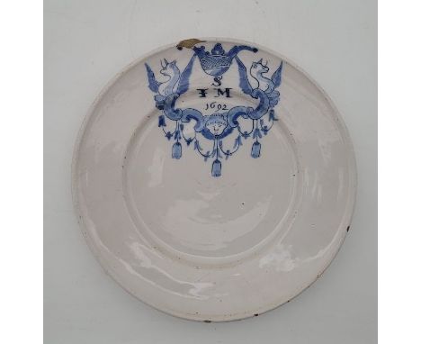 A late 17th century English Delftware plate, underglaze painted in blue with griffins and SFM 1692", diameter 22.3cm.Conditio