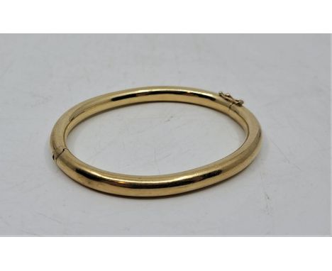 A 9ct. gold hinged eliptical bangle, interior dimensions aprrox. 62mm x 50mm. (12.7g)
