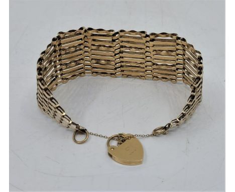 A wide 9ct. gold gate bracelet, with 9ct. gold heart padlock clasp, width 3.4cm, length approx. 18.5cm. (18.7g)
