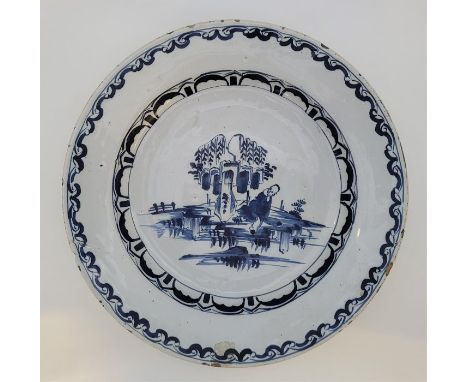An 18th century Bristol Delftware charger, painted in blue, diameter 34.3cm, height 5.3cm.Condition note: loss of glaze to ri