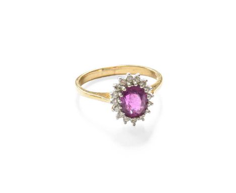 A 9 Carat Gold Ruby and Diamond Cluster Ring, the oval cut ruby within a border of round brilliant cut diamonds, in white cla