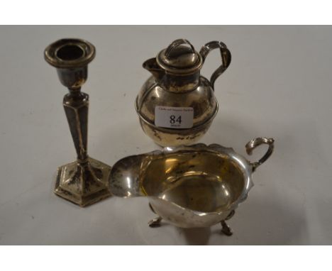 A silver sauce boat; a silver Guernsey cream jug; and a silver candlestick 
