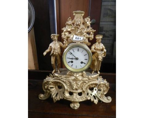 A gilded mantel clock surmounted figures.