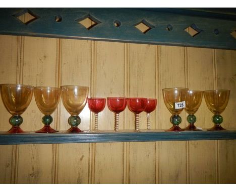 Six coloured glass goblets and four part cranberry glass wine sampler glasses.