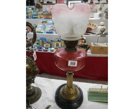 A Victorian oil lamp on pot base with brass column, ruby glass font and later shade. (converted to electric).