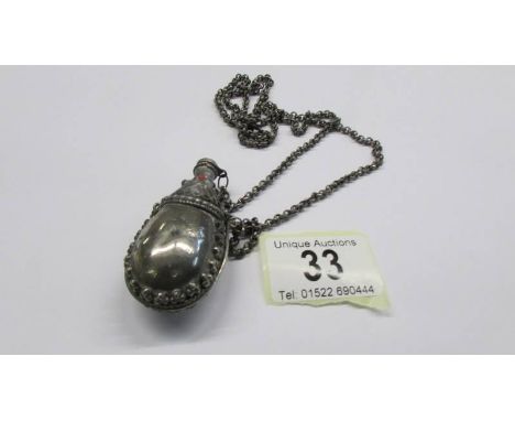 An old white metal perfume bottle on chain.