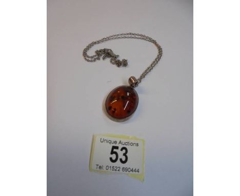 An amber coloured pendant on unmarked white metal chain.
