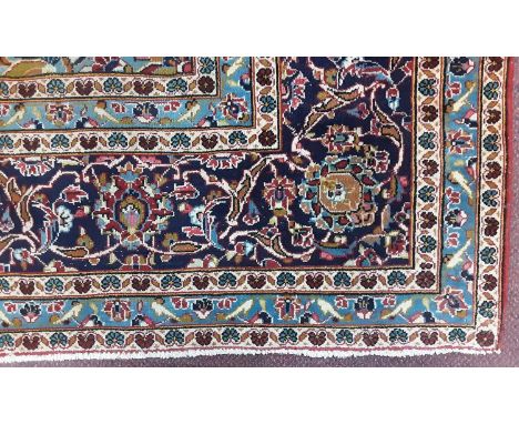 LARGE BORDERED CARPET OF KASHAN DESIGN, with stylised floral and foliate decoration to nay blue and turquoise ground355cm x 2