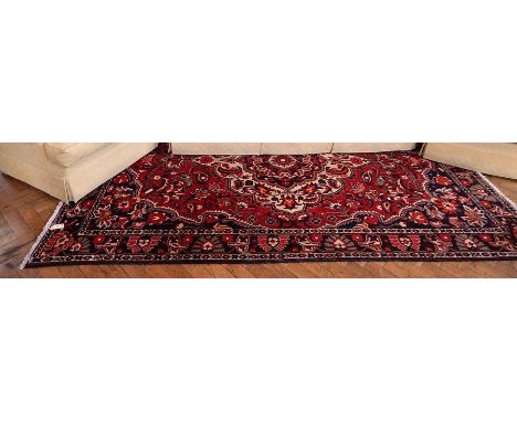 Persian style wool rug with central medallion, allover stylised floral and foliate decorated in shades of red, blue and cream