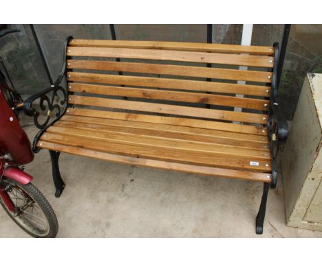 A WOODEN SLATTED GARDEN BENCH WITH DECORATIVE CAST BENCH ENDS 