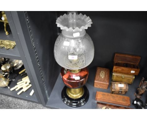 A fine Victorian oil lamp having ceramic and brass base with cranberry glass well and formed etched glass shade. 54cm tall. I
