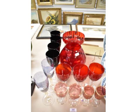 A selection of colour glass wares including four black wine glasses, three large red wine glasses, four smaller etched wine g