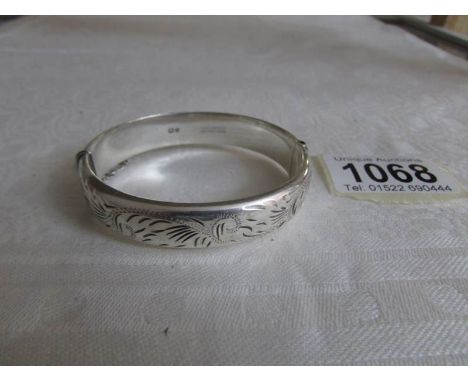 A silver engraved bangle with safety chain