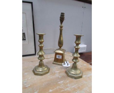 A brass lamp base and a pair of brass candlesticks