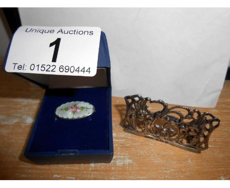 A silver place card holder and a silver and enamel brooch