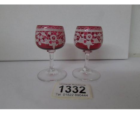 A pair of miniature cranberry glass goblets with enamel decoration