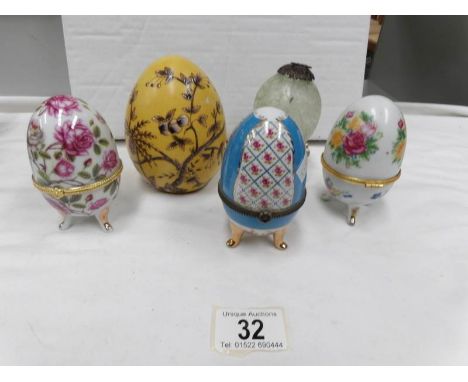 A hand decorated ceramic egg together with 3 egg shaped trinket pots and a glass hanging egg
