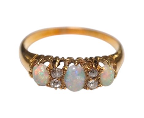 An early 20th century yellow metal and three stone white opal ring, with four stone diamond chip spacers, size M/N, gross wei