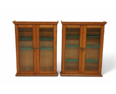 Pair of golden oak display cabinets, projecting moulded cornice over two bevel glazed doors, fitted with adjustable shelves D