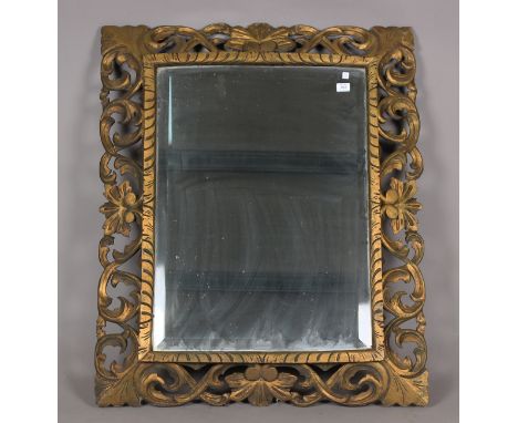 A 20th century giltwood wall mirror with a foliate scroll frame and bevelled glass, 114cm x 93cm.Buyer’s Premium 29.4% (inclu