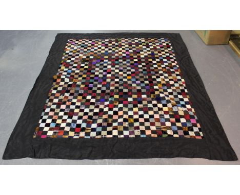 A 20th century patchwork bedcover, worked from silk, velvet and other fabric specimens, mounted within a black silk border an