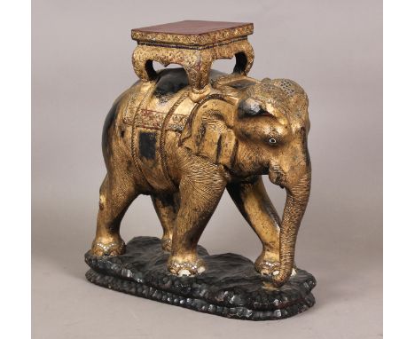 A 20th century Indian carved wooden model of an elephant wearing a howdah, the gilded surface inset with mirrored panels, hei