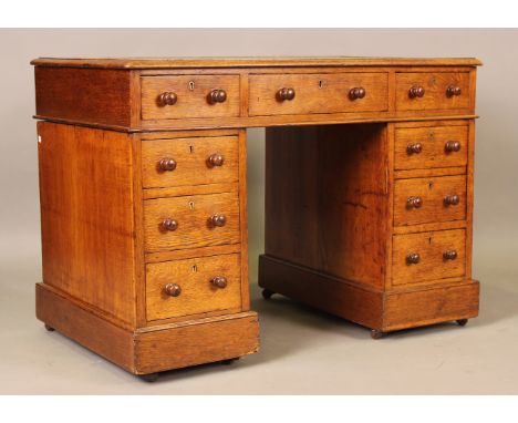 A late Victorian oak twin pedestal desk, the moulded top inset with gilt-tooled leather above an arrangement of drawers, heig