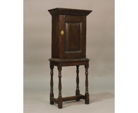 A small 17th century oak cupboard, fitted with a panelled door, raised on turned and block legs, height 108cm, width 44cm, de