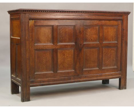 A late 18th/19th century provincial oak cupboard, the dentil moulded pediment above two fielded panel doors, on stile legs, h