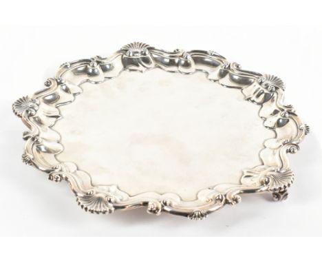BARKER BROS; an Edwardian hallmarked silver tray of shaped circular form, with scallop moulded stepped border and raised on t
