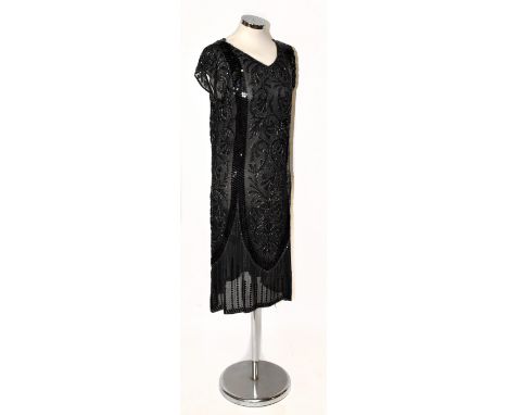 A 1920s black silk V-neck sleeveless flapper dress heavily beaded with decorative sequins, including a black and silver bugle