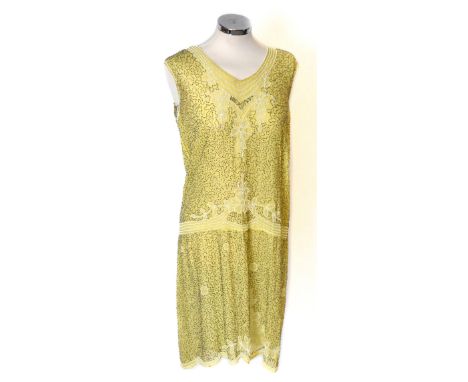 A 1920s yellow silk V-neck sleeveless flapper dress heavily beaded with decorative bugle beads and white beads of foliate des