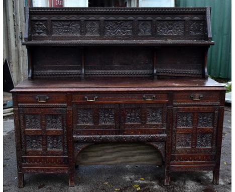 A late Victorian carved oak sideboard with shelved panel back above three drawers and doors, with later speaker mounted to ce