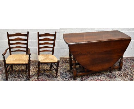 A reproduction oak oval drop leaf dining table with end drawer on turned gateleg supports, also a set of nine (8+1) rush seat