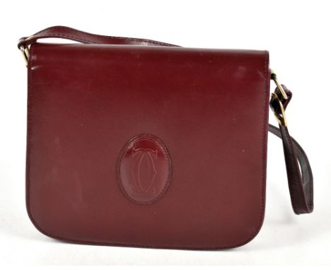 CARTIER; a vintage burgundy Bordeaux leather shoulder bag with large embossed logo to front, gold tone hardware buckles to si