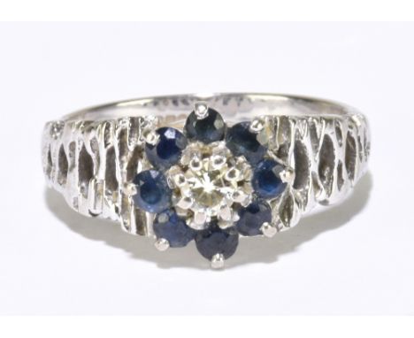 An 18ct white gold sapphire and diamond reverse cluster ring with pierced bark effect shoulders, size M, approx. 4.85g.&nbsp;