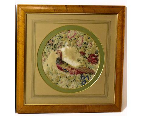 A 19th century stump work tapestry panel depicting a pheasant amongst flowers, diameter 33cm, in a maple veneered frame.