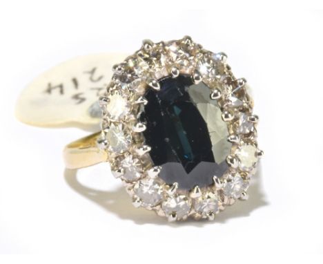 An 18ct yellow gold sapphire and diamond oval cluster ring, the mixed cut sapphire set within a border of fourteen round bril