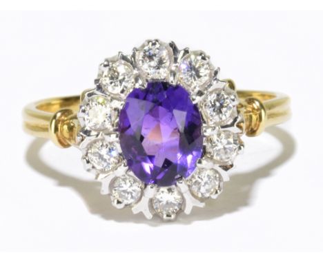 An 18ct yellow gold diamond and amethyst cluster ring the central oval cut amethyst within a border of ten round brilliant cu