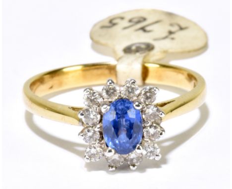 An 18ct yellow gold sapphire and diamond cluster ring, centred with a pale blue sapphire within a border of twelve brilliant 