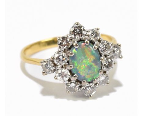 An 18ct yellow gold opal and diamond cluster ring, the central oval cabochon opal within a border of twelve round brilliant c