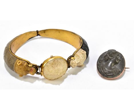 An unusual 19th century Continental yellow metal and carved volcanic lava bangle, with central flower head flanked by stylise