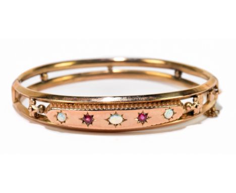 An Edwardian 9ct rose gold opal and garnet oval hinged snap bangle, the platform set with central oval opal, twin circular ca