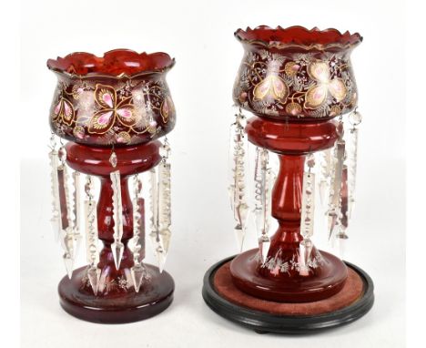 A pair of Victorian ruby glass lustres with gilt detailing and cut glass lustre drops, height 36cm, with one ebonised base an