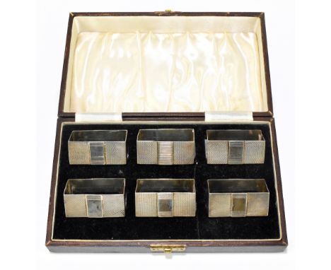 HARMAN BROS; a cased set of six George VI hallmarked silver napkin rings of rectangular form with engine turned decoration in