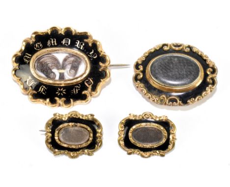 Four Victorian yellow metal and enamelled mourning brooches, the largest inscribed 'In Memory Of' with central hair compartme