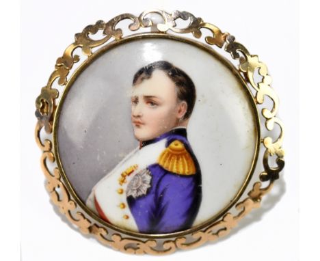 A circular yellow metal framed porcelain brooch depicting the profile portrait of Napoleon, within a scroll pierced frame, un
