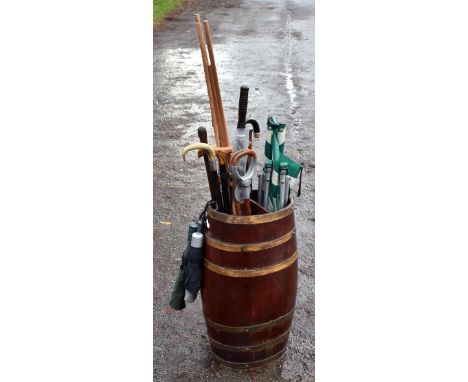 An early 20th century coopered oak stick stand, housing various walking sticks.