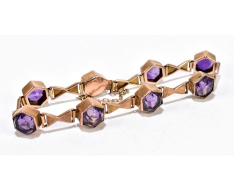 A yellow metal and amethyst line bracelet formed of eight hexagonal cut amethysts, with bow shaped links and box snap and saf