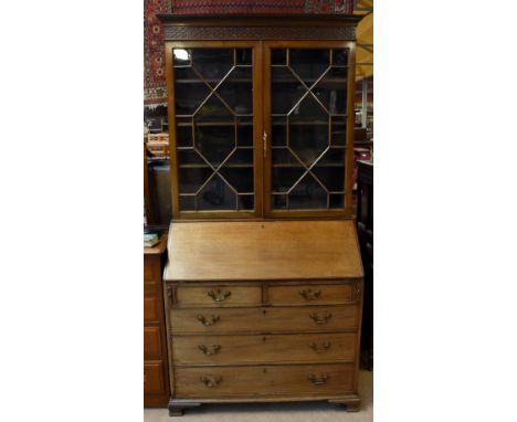 A Georgian mahogany bureau bookcase, the moulded cornice with blind fret decoration above the pair of astragal glazed doors w